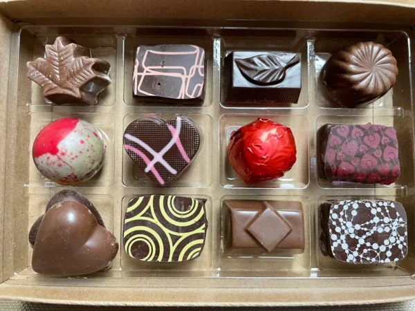 Cette boîte élégante contient 12 chocolats belges assortis, alliant chocolat blanc, noir et au lait. Chaque pièce est soigneusement sélectionnée pour une dégustation raffinée, idéale à offrir ou pour se faire plaisir.