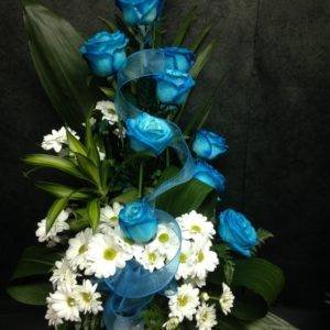 Arrangement floral avec roses bleues et fleurs blanches, parfait pour un hommage funéraire, la Saint-Valentin ou toute occasion spéciale.