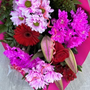 Bouquet floral éclatant avec des fleurs fuschia et rouges, parfait pour célébrer l’amour et les moments spéciaux.